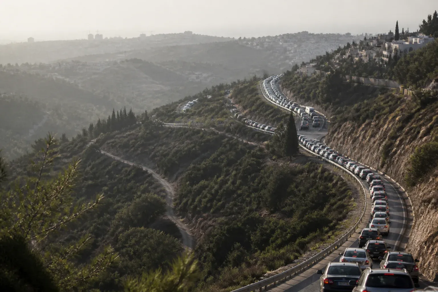 שורה ארוכה של מכוניות שזוחלות בכביש הררי בשעת עומס, מבט מלמעלה